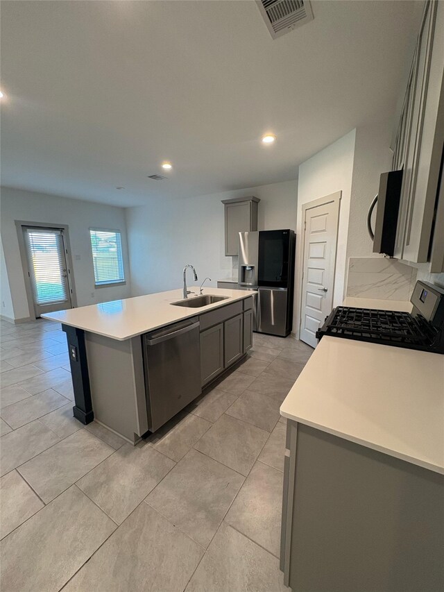 29506 Wilkerson Ln, Katy, TX 77494 - kitchen with stainless steel appliances, a sink, gray cabinets, an island with sink, and light countertops