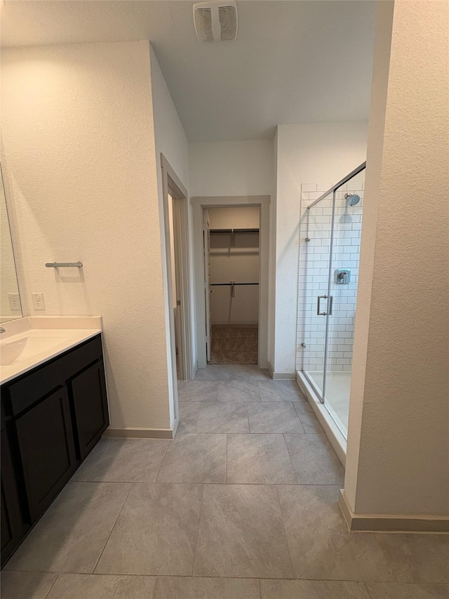29506 Wilkerson Ln, Katy, TX 77494 - bathroom featuring vanity, a stall shower, a spacious closet, baseboards, and a textured wall