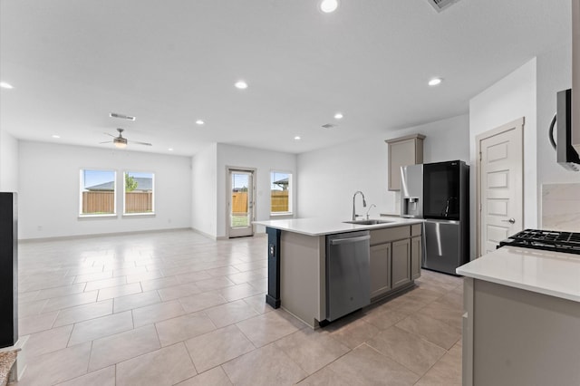 29506 Wilkerson Ln, Katy, TX 77494 - kitchen with stainless steel appliances, an island with sink, ceiling fan, gray cabinets, and light countertops