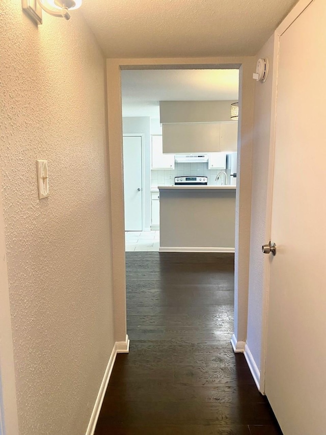 9000 Bissonnet St Unit 707, Houston, TX 77074 - hallway featuring a textured wall, dark wood-style flooring, and baseboards