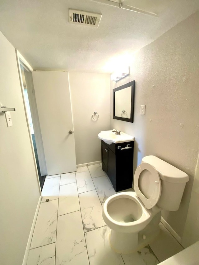 9000 Bissonnet St Unit 707, Houston, TX 77074 - bathroom featuring marble finish flooring, vanity, toilet, baseboards, and a textured wall