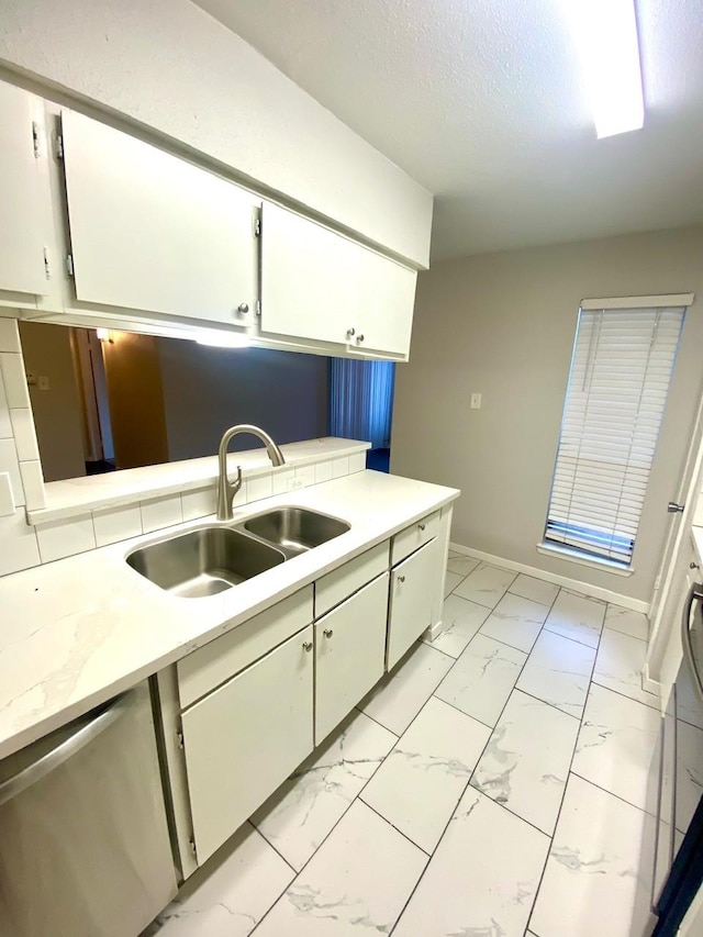 9000 Bissonnet St Unit 707, Houston, TX 77074 - kitchen featuring a sink, light marble finish floors, light countertops, baseboards, and white cabinetry