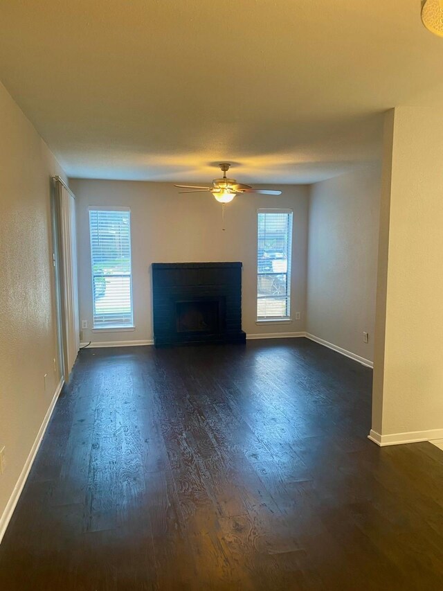 9000 Bissonnet St Unit 707, Houston, TX 77074 - unfurnished living room with dark wood finished floors, healthy amount of natural light, ceiling fan, and a fireplace with raised hearth