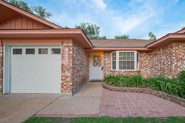 4210 Mona Lee Ln, Houston, TX 77080 - doorway to property with brick siding, an attached garage, board and batten siding, a shingled roof, and concrete driveway