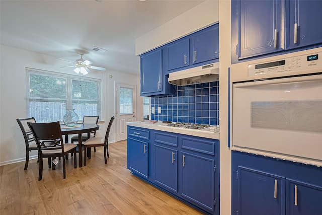 4210 Mona Lee Ln, Houston, TX 77080 - kitchen featuring blue cabinets, white oven, under cabinet range hood, and decorative backsplash