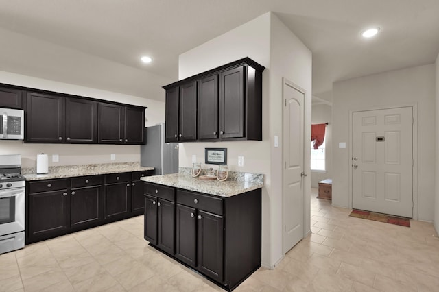 9923 Berlandier Ash Ln, Tomball, TX 77375 - kitchen with appliances with stainless steel finishes, dark cabinetry, light tile patterned floors, light stone countertops, and recessed lighting