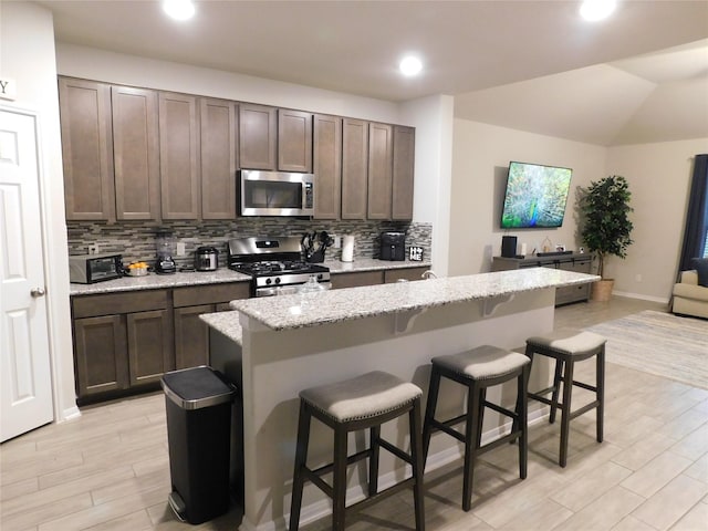 14827 Fairy Tern Ln, Houston, TX 77049 - kitchen featuring stainless steel appliances, backsplash, recessed lighting, a breakfast bar area, and light wood-style floors