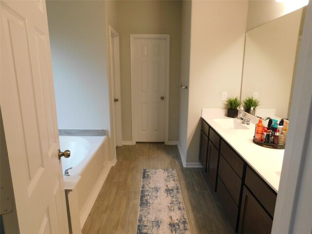 14827 Fairy Tern Ln, Houston, TX 77049 - bathroom featuring wood finished floors, a garden tub, double vanity, and baseboards