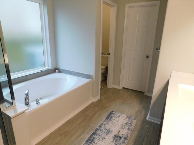 14827 Fairy Tern Ln, Houston, TX 77049 - full bath with a bath, toilet, vanity, wood finished floors, and baseboards