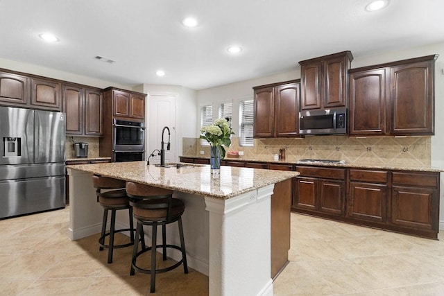 266 Overland Trce, Montgomery, TX 77316 - kitchen with appliances with stainless steel finishes, a sink, recessed lighting, light stone counters, and a kitchen island with sink