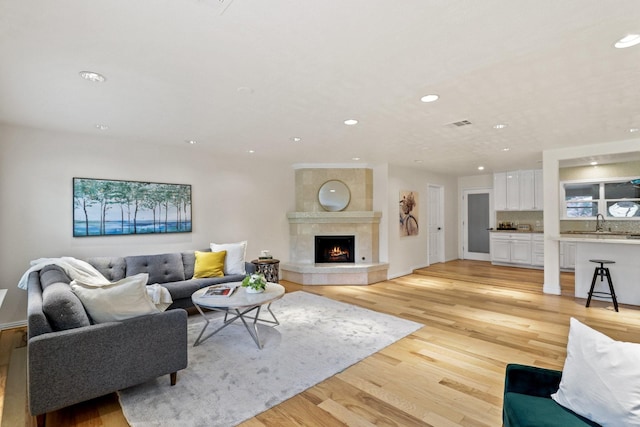 10328 Shadow Oaks Dr, Houston, TX 77043 - living room featuring recessed lighting, light wood-type flooring, a tiled fireplace, and baseboards
