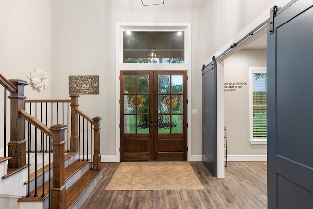 19817 Whispering Creek Trl, Magnolia, TX 77355 - foyer entrance featuring a barn door, wood finished floors, baseboards, and french doors