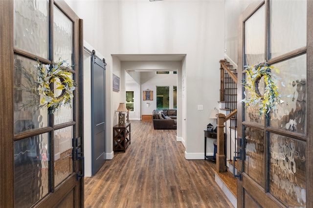 19817 Whispering Creek Trl, Magnolia, TX 77355 - foyer entrance with a barn door, dark wood finished floors, a towering ceiling, and baseboards