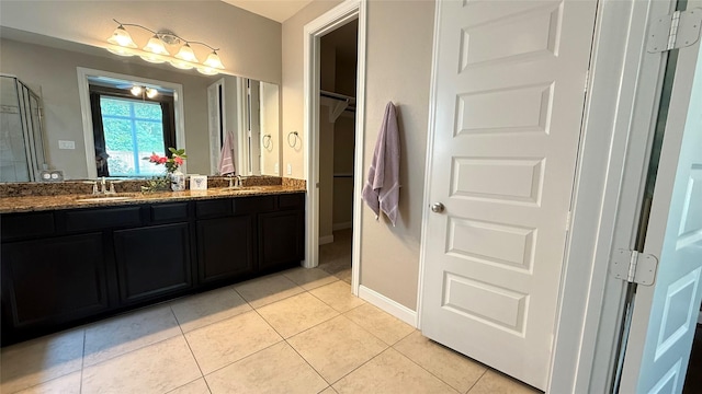 3021 Rocky Point Dr, Pearland, TX 77584 - bathroom with double vanity, tile patterned flooring, baseboards, a walk in closet, and an enclosed shower