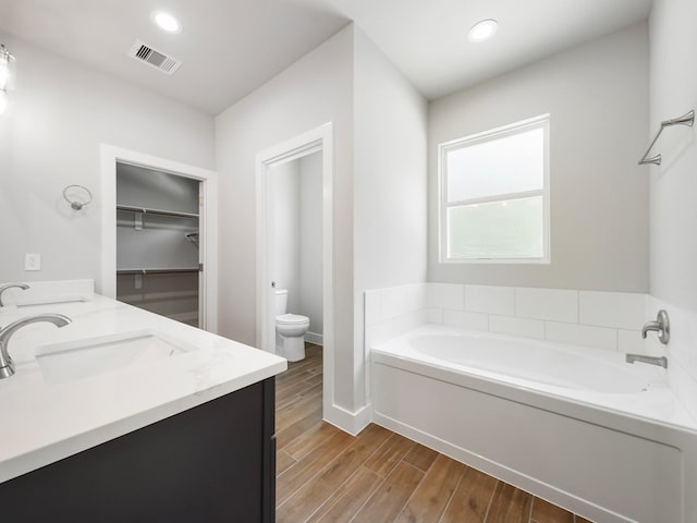 731 Magnolia Point Dr, Houston, TX 77336 - full bathroom with a bath, toilet, wood finished floors, double vanity, and baseboards