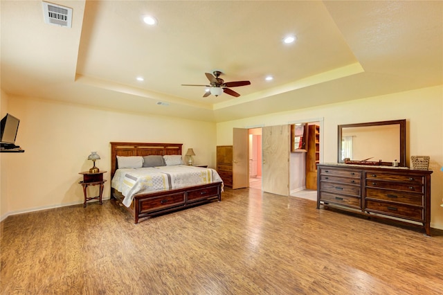 2465 Ryan Dr, Alvin, TX 77511 - bedroom featuring wood finished floors, a tray ceiling, baseboards, recessed lighting, and ensuite bath