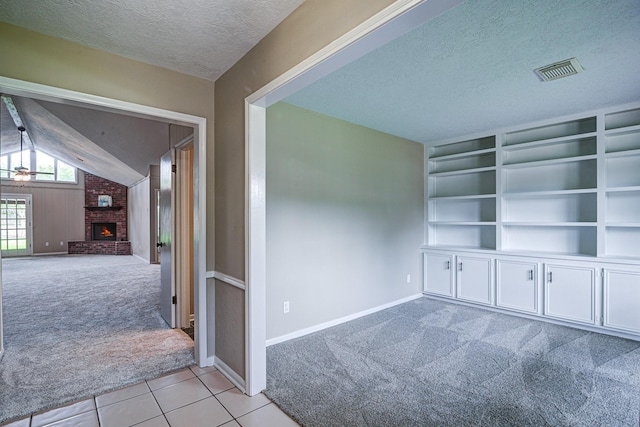 1313 Mcdonald St, Deer Park, TX 77536 - tiled spare room with carpet floors, a textured ceiling, baseboards, a fireplace, and built in shelves