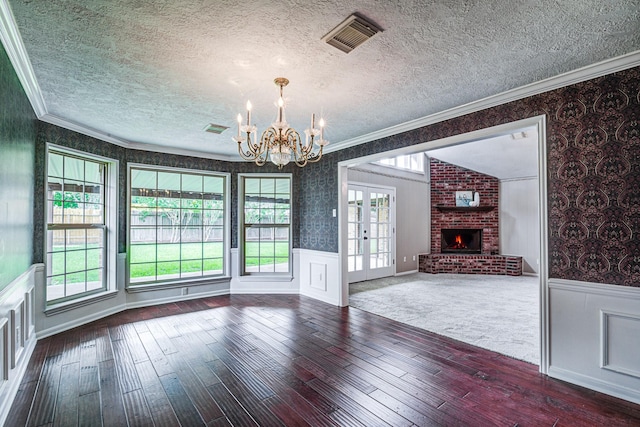 1313 Mcdonald St, Deer Park, TX 77536 - unfurnished living room featuring a chandelier, a textured ceiling, crown molding, dark wood-style floors, and french doors
