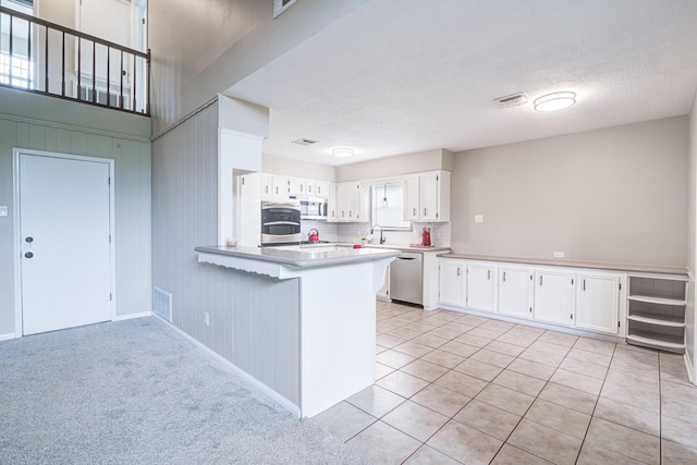 1313 Mcdonald St, Deer Park, TX 77536 - kitchen with stainless steel appliances, a peninsula, white cabinets, light countertops, and a textured ceiling