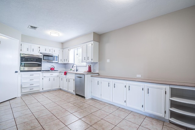 1313 Mcdonald St, Deer Park, TX 77536 - kitchen with appliances with stainless steel finishes, tasteful backsplash, white cabinetry, a textured ceiling, and light tile patterned floors
