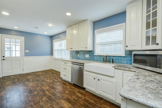 5007 Redstart St, Houston, TX 77035 - kitchen with appliances with stainless steel finishes, a sink, a wainscoted wall, white cabinetry, and dark wood-style floors