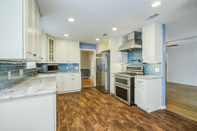 5007 Redstart St, Houston, TX 77035 - kitchen featuring appliances with stainless steel finishes, wall chimney range hood, tasteful backsplash, white cabinets, and recessed lighting