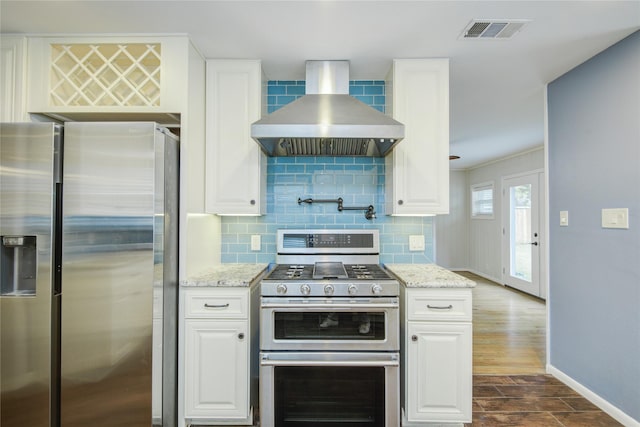 5007 Redstart St, Houston, TX 77035 - kitchen featuring appliances with stainless steel finishes, wall chimney range hood, backsplash, and white cabinets