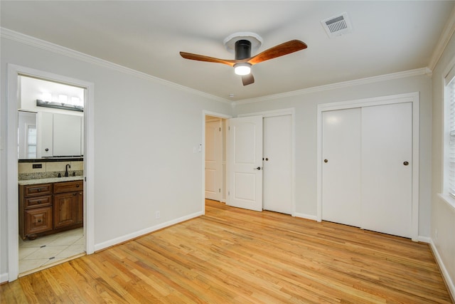 5007 Redstart St, Houston, TX 77035 - unfurnished bedroom featuring multiple closets, a sink, light wood finished floors, ornamental molding, and ensuite bathroom