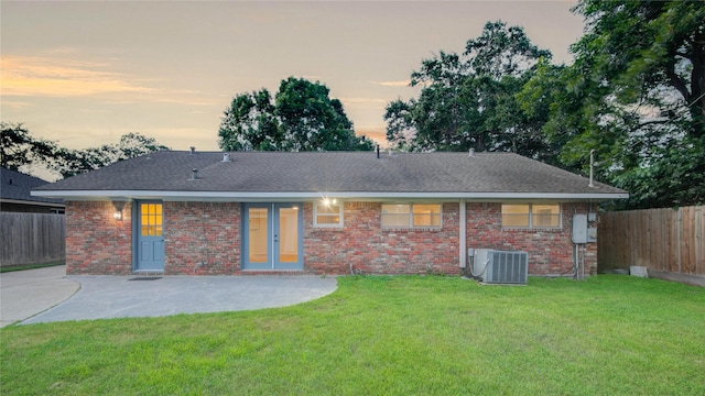 5007 Redstart St, Houston, TX 77035 - back of house at dusk featuring central air condition unit, a patio, brick siding, and a shingled roof