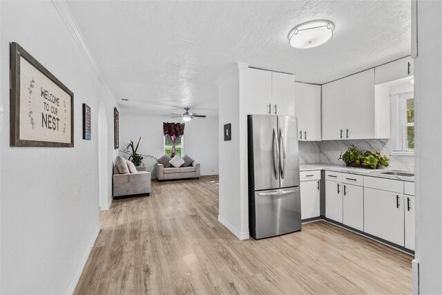 7650 US Highway 69 S, Woodville, TX 75979 - kitchen with freestanding refrigerator, light countertops, light wood-type flooring, white cabinetry, and backsplash