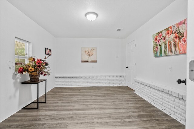 7650 US Highway 69 S, Woodville, TX 75979 - unfurnished room with wainscoting, wood finished floors, and brick wall