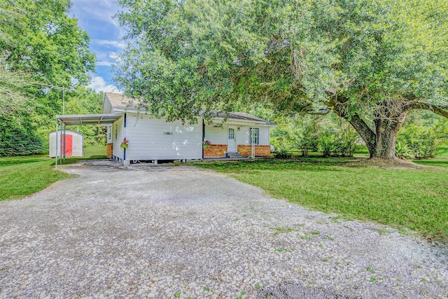 7650 US Highway 69 S, Woodville, TX 75979 - view of front of home with driveway, a front yard, a shed, and a carport
