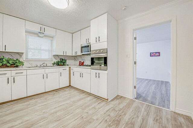 7650 US Highway 69 S, Woodville, TX 75979 - kitchen with stainless steel appliances, light wood finished floors, backsplash, light countertops, and a textured ceiling