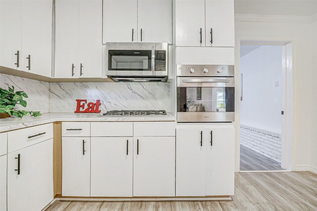 7650 US Highway 69 S, Woodville, TX 75979 - kitchen featuring appliances with stainless steel finishes, light countertops, light wood-style flooring, white cabinets, and crown molding