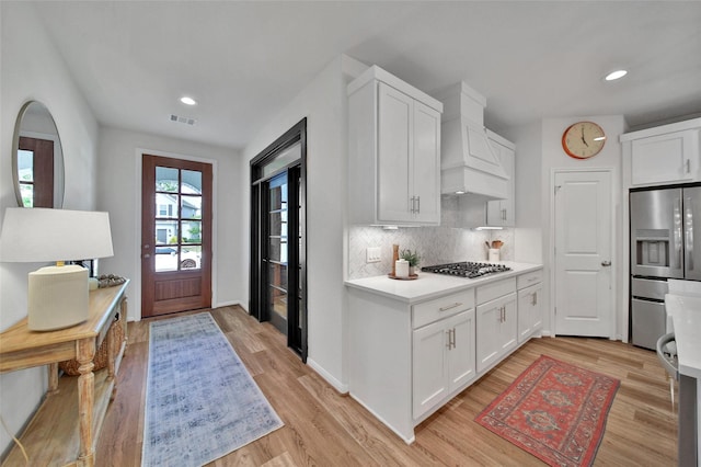 2331 Hagerman Rd, Conroe, TX 77384 - kitchen featuring appliances with stainless steel finishes, wall chimney exhaust hood, backsplash, light wood-type flooring, and recessed lighting