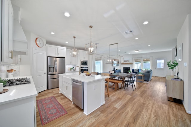 2331 Hagerman Rd, Conroe, TX 77384 - kitchen featuring appliances with stainless steel finishes, white cabinetry, light wood-style floors, light countertops, and recessed lighting