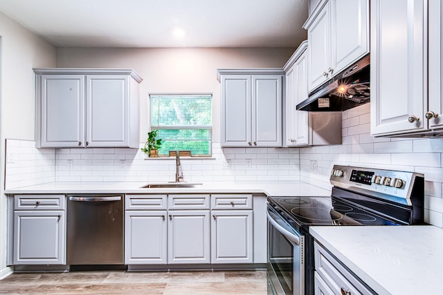 4403 2nd St, Bacliff, TX 77518 - kitchen featuring appliances with stainless steel finishes, under cabinet range hood, a sink, tasteful backsplash, and light countertops