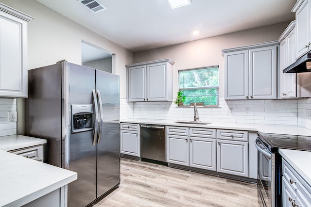 4403 2nd St, Bacliff, TX 77518 - kitchen featuring stainless steel appliances, a sink, light wood finished floors, decorative backsplash, and light countertops