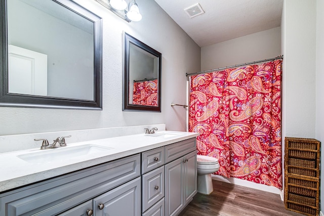 4403 2nd St, Bacliff, TX 77518 - full bathroom with double vanity, wood finished floors, toilet, a shower with shower curtain, and baseboards