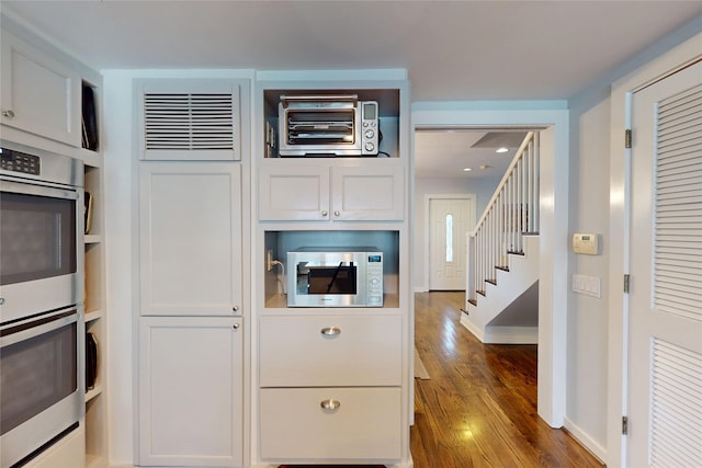 2737 Werlein Ave, Houston, TX 77005 - kitchen with white microwave, double oven, baseboards, wood finished floors, and white cabinetry