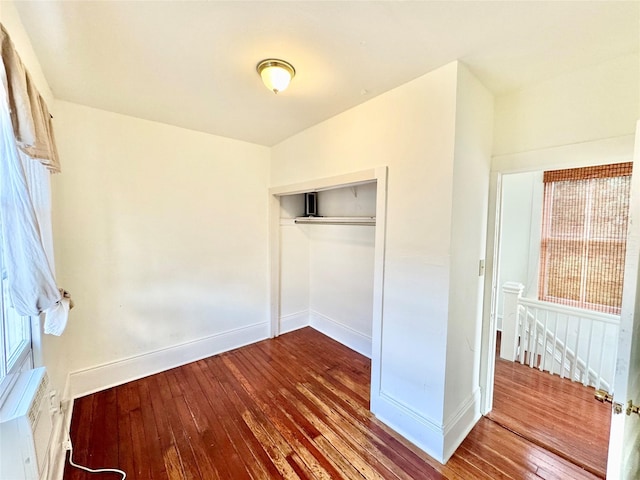 1317 Church St, Galveston, TX 77550 - unfurnished bedroom with wood-type flooring, baseboards, a closet, and a wall mounted AC