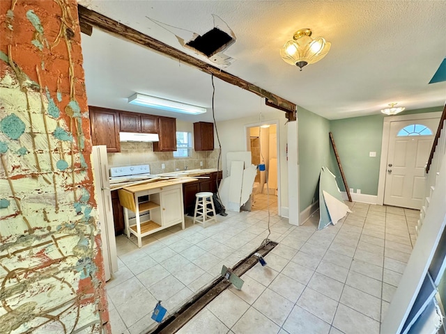1317 Church St, Galveston, TX 77550 - kitchen featuring under cabinet range hood, decorative backsplash, light tile patterned floors, light countertops, and baseboards