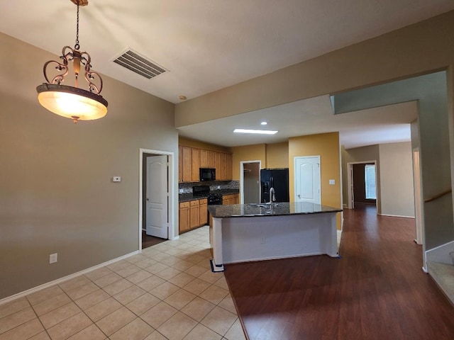19518 Grand Colony Ct, Katy, TX 77449 - kitchen featuring black appliances, decorative backsplash, baseboards, a kitchen island with sink, and pendant lighting