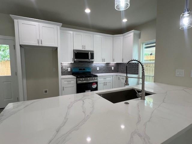 10516 Exeter St, Houston, TX 77093 - kitchen featuring stainless steel appliances, decorative backsplash, white cabinetry, light stone countertops, and decorative light fixtures