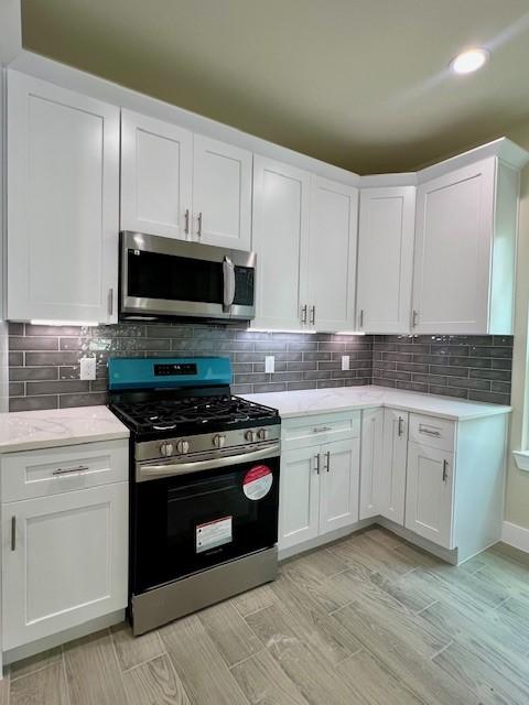 10516 Exeter St, Houston, TX 77093 - kitchen featuring appliances with stainless steel finishes, white cabinetry, backsplash, and recessed lighting