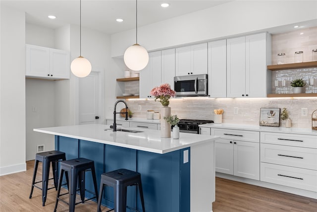 5306 San Juan St, Houston, TX 77020 - kitchen featuring open shelves, stainless steel microwave, a sink, stove, and light wood-style flooring