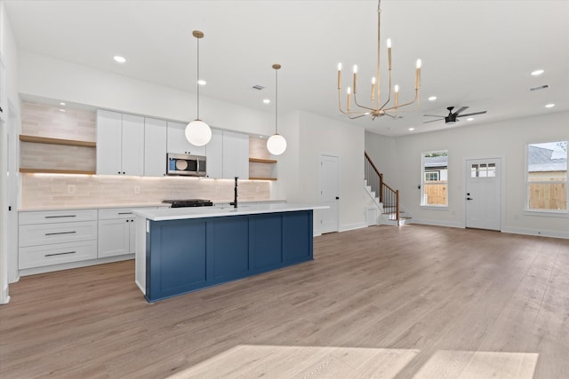 5306 San Juan St, Houston, TX 77020 - kitchen featuring stainless steel microwave, open shelves, backsplash, light countertops, and recessed lighting