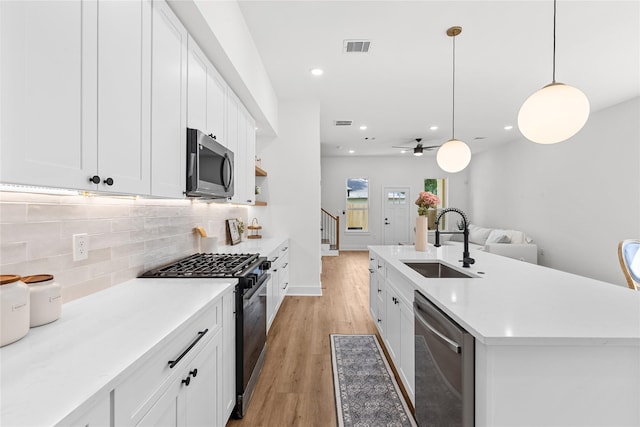 5306 San Juan St, Houston, TX 77020 - kitchen with appliances with stainless steel finishes, a sink, tasteful backsplash, light wood-type flooring, and white cabinets