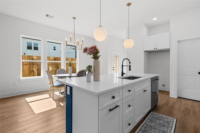 5306 San Juan St, Houston, TX 77020 - kitchen with a sink, stainless steel dishwasher, a chandelier, light wood-style floors, and white cabinets