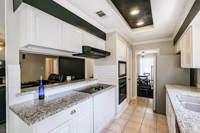 1510 Elmscott Dr, Sugar Land, TX 77498 - kitchen with black appliances, under cabinet range hood, a raised ceiling, light tile patterned flooring, and white cabinetry
